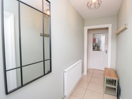 A hallway with a mirror, radiator, and door at Rothay Cottage in Ambleside