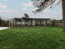A house with a deck and grass in front at The Bay in Benllech