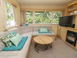 A sitting area with an L shaped sofa cushions a round coffee table a television and large windows at Greenwood in Cowes