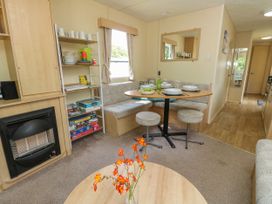 A dining area with a table set with plates glasses and a bottle of wine next to a fireplace and shelves with dishes and board games at Greenwood in Cowes