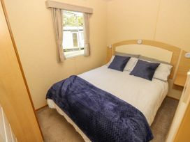 A bedroom with a double bed featuring striped bedding and blue pillows at Greenwood in Cowes
