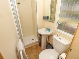 A bathroom with a shower, sink, toilet, mirror, and frosted window at Greenwood in Cowes