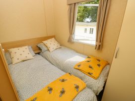 A bedroom with two single beds with bee patterned blankets and pillows at Greenwood in Cowes