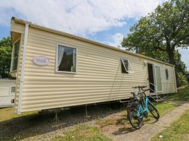A beige mobile home with two bicycles parked outside near an open door under a tree at Greenwood in Cowes