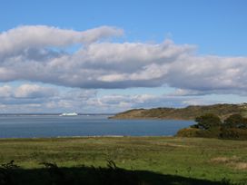 A coastal landscape with green fields in the foreground water and hills in the background at Greenwood in Cowes