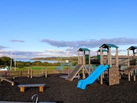 An outdoor playground with slides swings and climbing structures near a body of water at Greenwood in Cowes