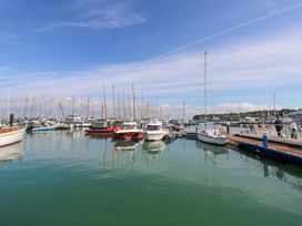 A marina with multiple sailboats and motorboats docked near a pier at Greenwood in Cowes