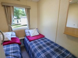 A small bedroom with two single beds with blue plaid bedding and decorative pillows at Greenwood in Cowes
