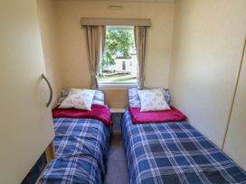 A bedroom with two single beds with checked bedding and red blankets under a window with curtains at Greenwood in Cowes
