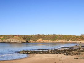 A beach with water and cliffs at Gwynlys in Cemaes Bay
