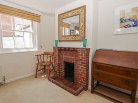 A living room with a fireplace and a chair at Iona Cottage in Southwold