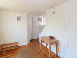 A hallway with a table, bowl, and painting at Iona Cottage in Southwold