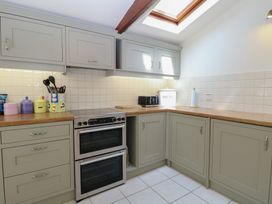 A kitchen with cabinets, a countertop, and an oven at Iona Cottage Southwold