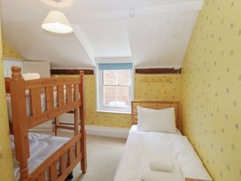 A bedroom with a bunk bed and a single bed at Iona Cottage in Southwold