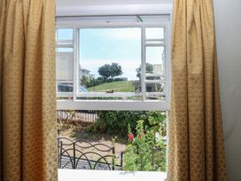 A window with curtains overlooking a garden at Iona Cottage Southwold
