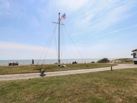 An outdoor area with a flagpole and a bench near the sea at Iona Cottage Southwold