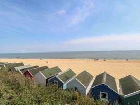 A view of beach huts with a sandy beach and sea at Iona Cottage in Southwold