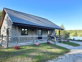 A wooden lodge with a deck and flowers outside at Kingfisher Lodge in Treverbyn near St Austell