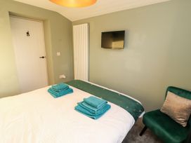 A bedroom with a bed, towels on top, television, radiator, and a chair at 10 Keekle Terrace in Keekle near Cleator Moor