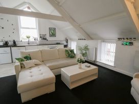 A living room with a sofa and kitchen area at The Old Workshop in Dre-Fach near Lampeter