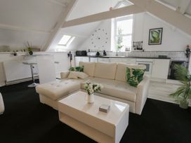 A living room with a sofa and kitchen area at The Old Workshop in Dre-Fach near Lampeter