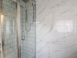 A shower with glass door and wall tiles at The Old Workshop in Dre-Fach near Lampeter