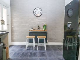 A kitchen area with two stools a small shelf with plants a wall clock and a black refrigerator at Terrace View in Trefriw near Llanrwst