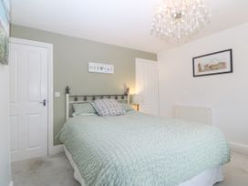A bedroom with a bed covered with a quilt and pillows two closed doors a standing lamp and framed pictures on the walls at Terrace View in Trefriw near Llanrwst