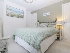 A bedroom with a bed covered in green bedding a bedside table with a lamp and artwork on the walls at Terrace View in Trefriw near Llanrwst