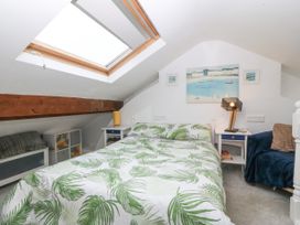 A bedroom with a bed with leaf patterned bedding a skylight a lamp on a bedside table and a chair at Terrace View Trefriw near Llanrwst