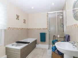 A bathroom with a bathtub shower sink towels and a mirror at Terrace View in Trefriw near Llanrwst
