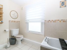 A bathroom with a toilet a window with blinds a bathtub and tiled walls at Terrace View in Trefriw near Llanrwst