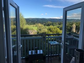 View from a balcony with a small table and chairs overlooking trees and hills at Terrace View in Trefriw near Llanrwst