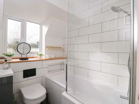 A bathroom with a bath, shower, and sink at 20 Honeycroft, Bourton-On-The-Water