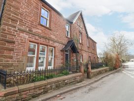 The exterior of a brick house with six windows a black metal gate and fence along a paved road at Allendale House in Armathwaite