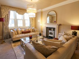 A living room with two sofas a glass coffee table a fireplace and a chandelier at Allendale House in Armathwaite
