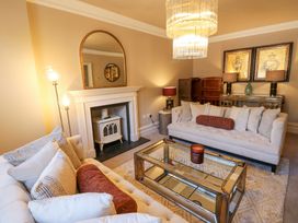 A living room with two sofas a glass coffee table a fireplace and a chandelier at Allendale House in Armathwaite