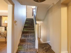 A staircase with patterned carpet and a hallway with wooden flooring at Allendale House in Armathwaite