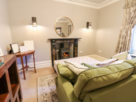 A living room with a green sofa a fireplace a round mirror on the wall and a wooden side table at Allendale House in Armathwaite