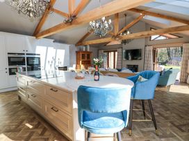 A kitchen and living area with blue chairs wooden beams and a television at Allendale House in Armathwaite
