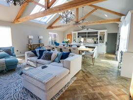 An open living room and kitchen with wooden beams and a dining table at Allendale House in Armathwaite