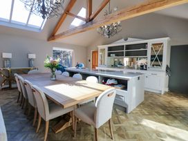 A dining area with a wooden table and chairs next to a kitchen island with cabinetry and a window at Allendale House in Armathwaite