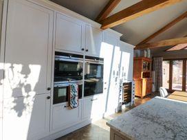 A kitchen with white cabinets built in ovens wooden beams and a wooden cupboard at Allendale House in Armathwaite