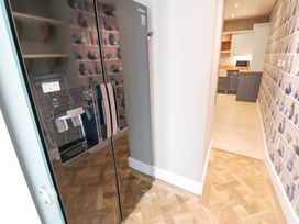 A kitchen hallway with a black refrigerator and patterned wallpaper at Allendale House in Armathwaite