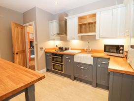 A kitchen with wooden countertops blue and white cabinets a double oven a sink and a microwave at Allendale House in Armathwaite