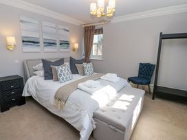 A bedroom with a bed and pillows a bench at the foot of the bed a blue chair and a window at Allendale House in Armathwaite