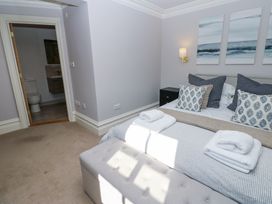 A bedroom with a bed with pillows and folded towels a bench at the foot of the bed and a doorway leading to a bathroom at Allendale House Armathwaite
