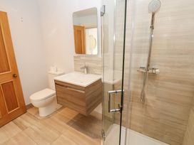 A bathroom with a toilet, a floating vanity with a sink and mirror, and a glass shower enclosure with a showerhead at Allendale House in Armathwaite
