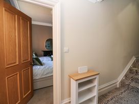 A hallway with a small white and wood shelf unit next to a staircase with zebra print carpet and a partially open door leading to a bedroom with beds at Allendale House in Armathwaite