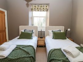 A bedroom with two single beds green pillows and knit blankets with a window between the beds at Allendale House in Armathwaite